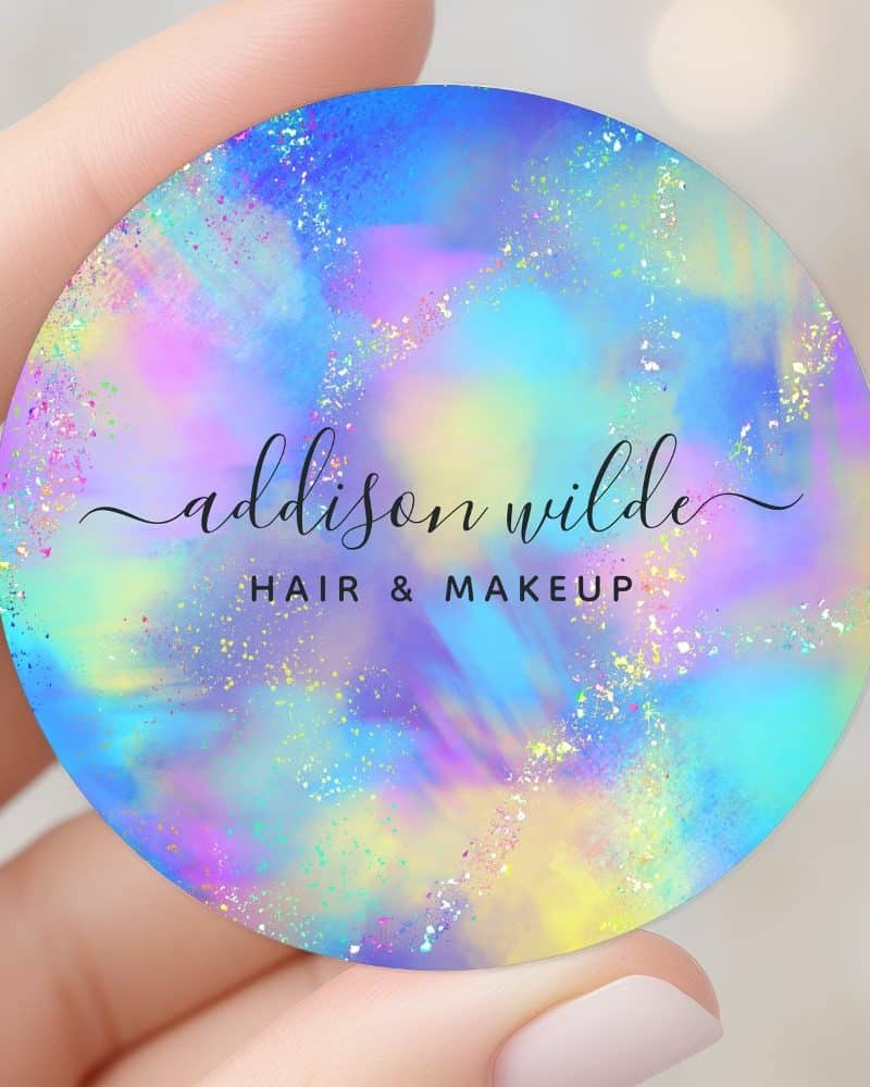 Round hair and makeup business card with iridescent pastel design and glitter. Addison Wilde is printed in elegant script.