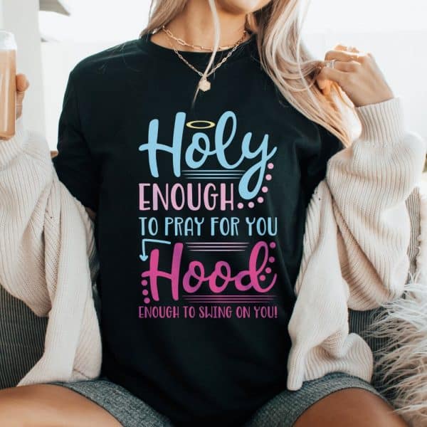 Woman Wearing A Black T-Shirt That Says Holy Enough To Pray For You, Hood Enough To Swing On You.