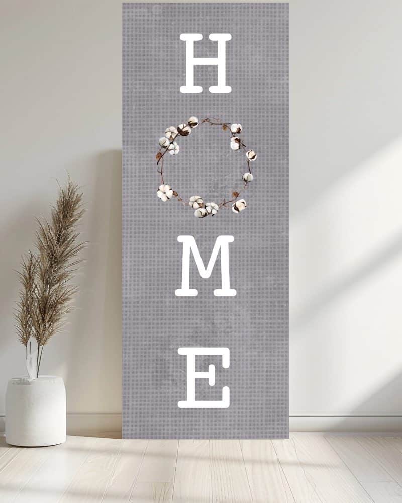 Gray canvas with the word HOME in white sans-serif font; a cotton wreath replaces the letter O.
