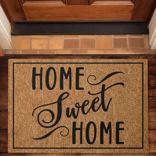 Tan Welcome Mat With Black Lettering That Says Home Sweet Home.