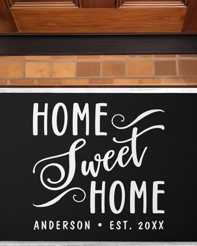 Black doormat with white script lettering reading Home Sweet Home and the last name Anderson with an established year.