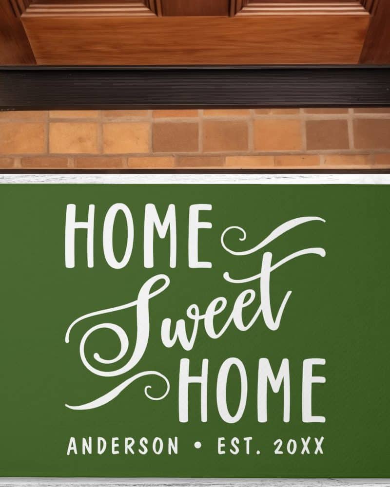 Dark green welcome mat with the words Home Sweet Home in a stylized white font, and a family name and establishment year below.