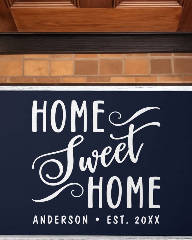 Navy blue doormat with the words Home Sweet Home in a stylized white script font, and the family name Anderson and establishment year below.