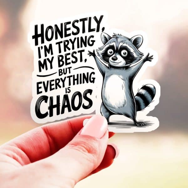 A Hand Holds A Sticker Featuring A Cartoon Raccoon With Arms Raised, Alongside Text That Reads, Honestly, I'M Trying My Best, But Everything Is Chaos.