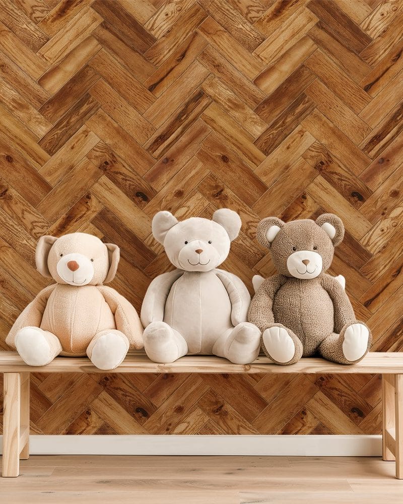 Three teddy bears sitting on a wooden bench in front of a herringbone wood pattern wall.