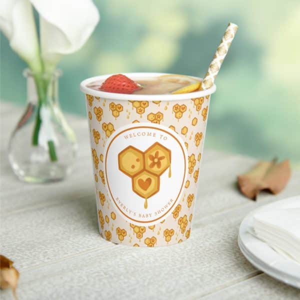 A Paper Cup With A Honey-Comb Themed Baby Shower Design, Filled With A Beverage And A Straw.
