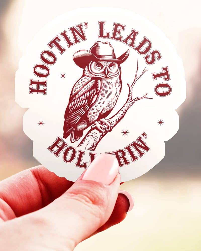 A hand holds up a sticker featuring a cowboy hat-wearing owl perched on a branch. The text around the owl reads Hootin Leads to Hollerin.