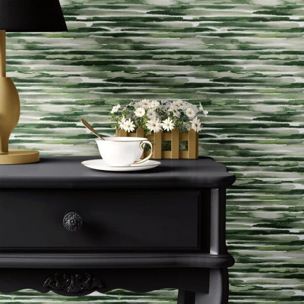 A Teacup And Saucer Sit On A Dark Wooden Side Table, In Front Of A Wall With Green Watercolor Stripes.