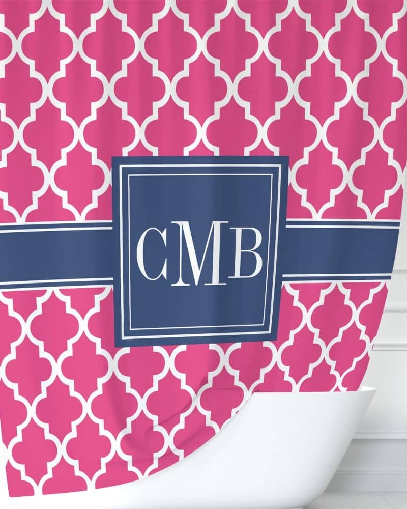 Pink shower curtain with a navy blue monogram and quatrefoil pattern.