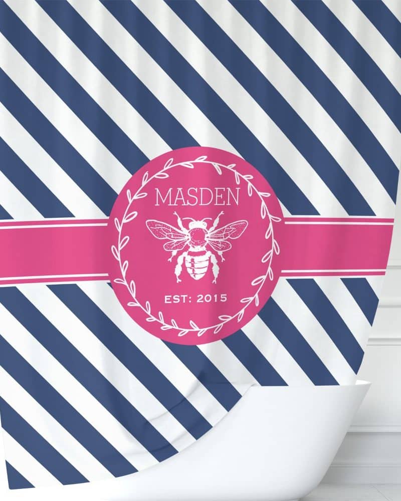 Navy and white striped shower curtain with a pink circle logo featuring a bee and the name Madsen.