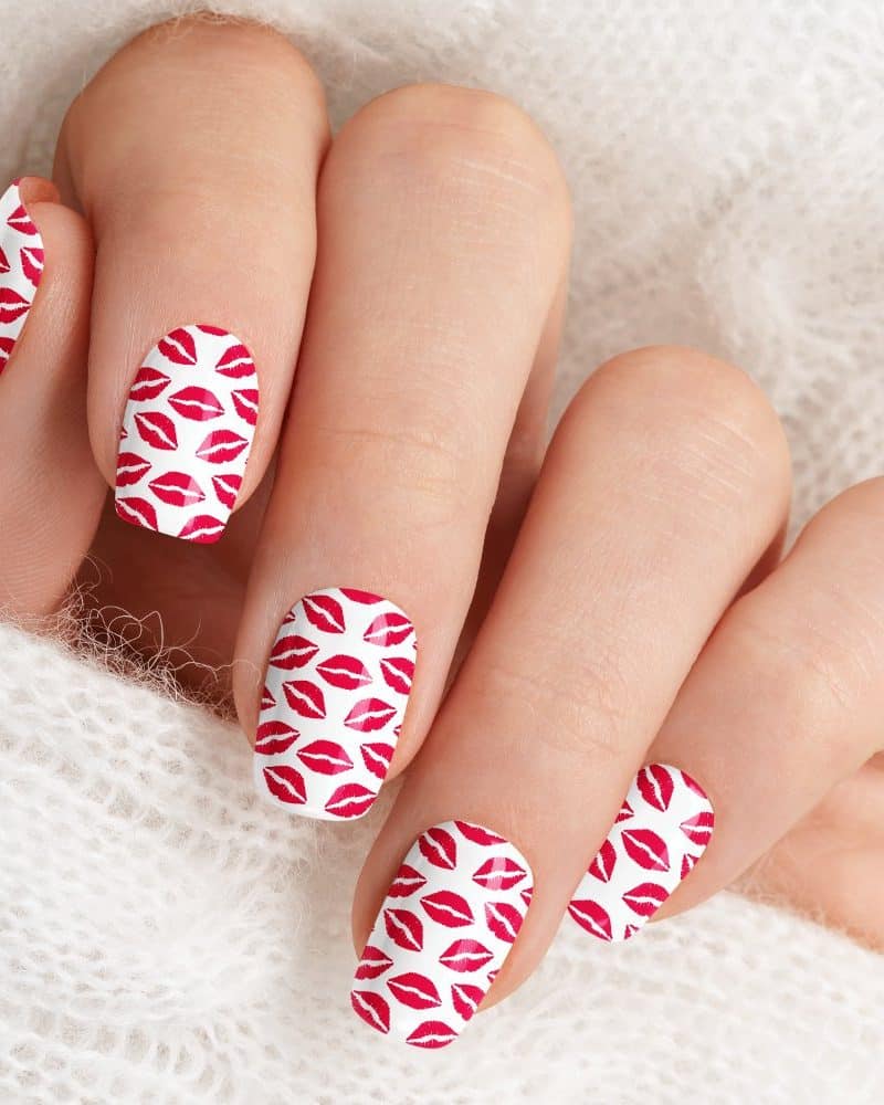 Close-up of a hand with fingernails decorated with a red lips pattern.