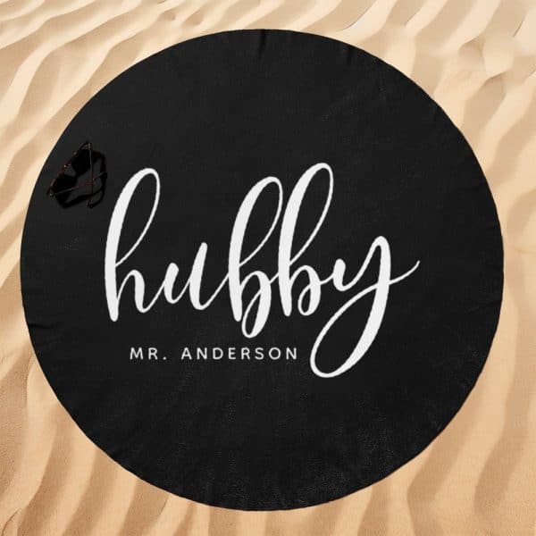 Black Round Beach Towel With The Word Hubby In White Cursive Lettering And Mr. Anderson Below It.