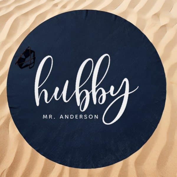 Navy Blue Round Beach Towel With The Word Hubby In White Script Lettering And Mr. Anderson Below It.