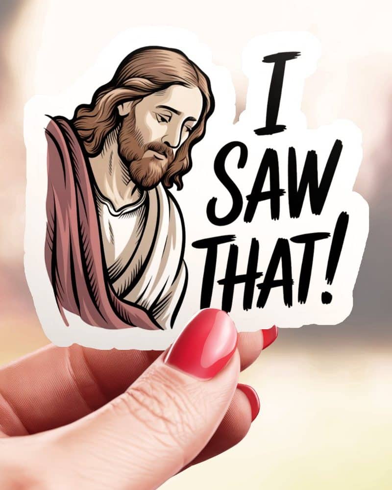 A hand holds a sticker depicting Jesus with the text I Saw That.