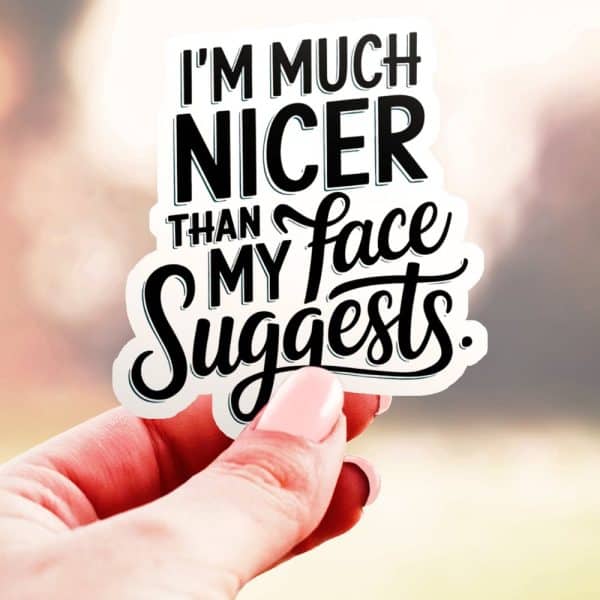 Hand Holding A Sticker That Says Im Much Nicer Than My Face Suggests.