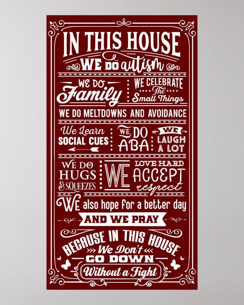 Burgundy-colored sign with white text proclaiming that in this house, we do autism, family, and celebrate the small things. We also accept, respect, and love hard.