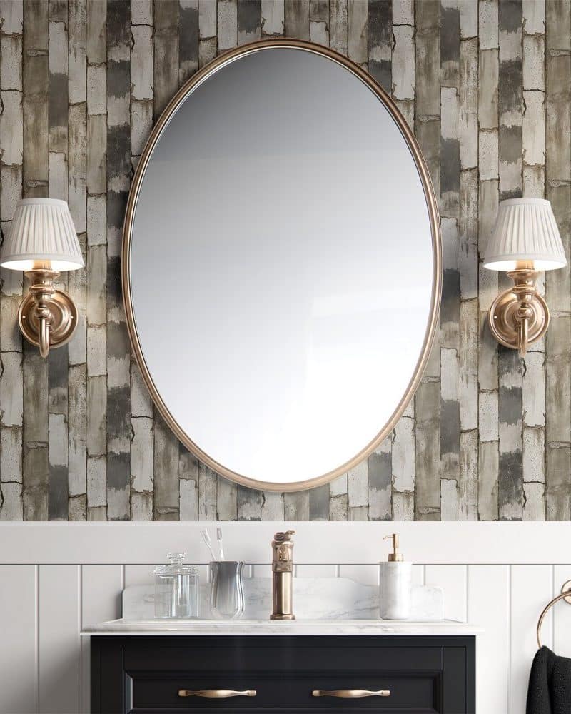 Large oval mirror above a bathroom vanity with gray and beige brick wallpaper.