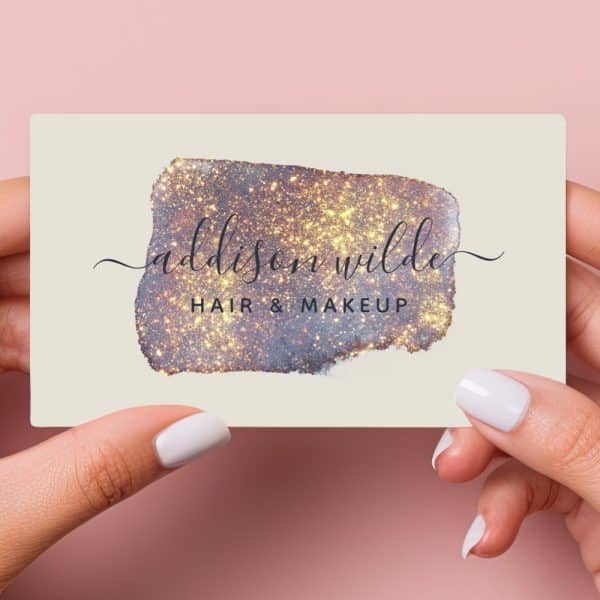 Two Hands Hold A Business Card Featuring A Sparkly Gold And Purple Design And The Name Addison Wilde, Hair &Amp; Makeup.