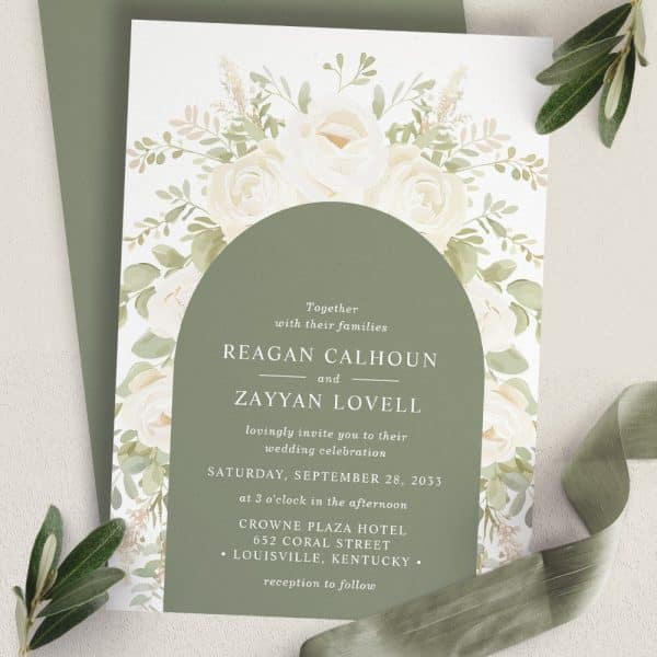 Wedding Invitation With White Roses And Greenery, Featuring The Names Reagan Calhoun And Zayyan Lovell.