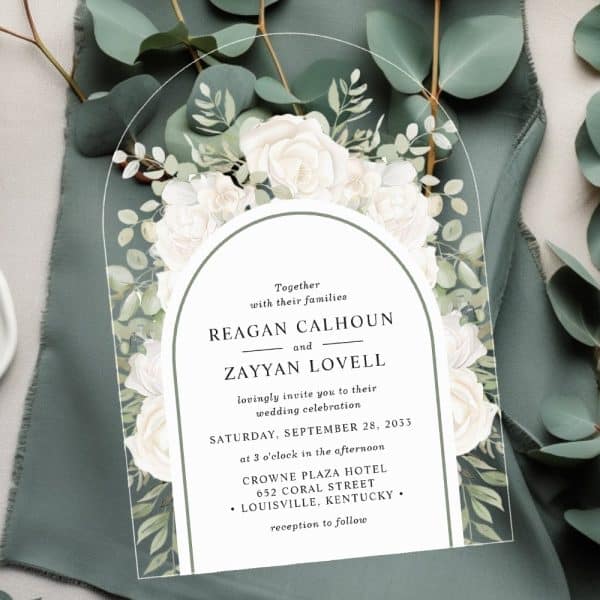Wedding Invitation With Arched Design, Featuring White Roses And Greenery, Announcing The Marriage Of Reagan Calhoun And Zayyan Lovell.