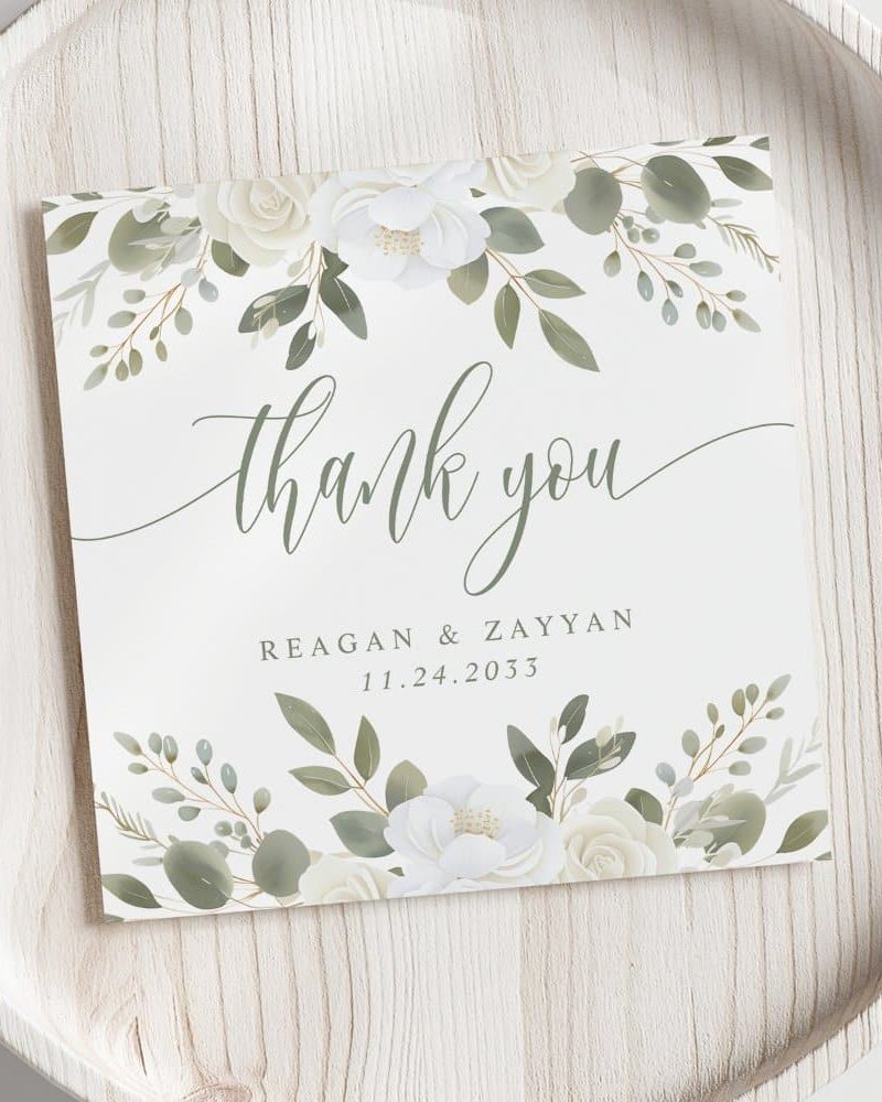 Wedding thank you card with white flowers and green leaves.