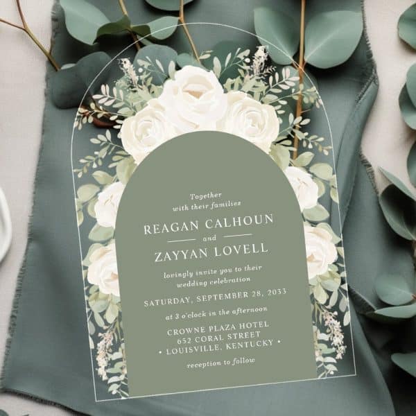 Wedding Invitation With White Roses And Greenery, Featuring The Names Reagan Calhoun And Zayyan Lovell.