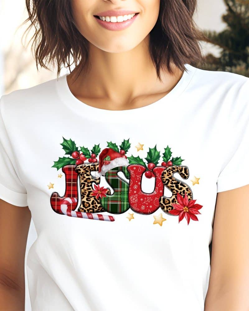 White t-shirt with a Christmas design featuring the word JESUS in festive patterns and colors.