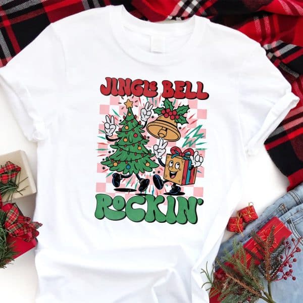 White T-Shirt With A Christmas Design Featuring A Cartoon Christmas Tree And Present Dancing. The Text Jingle Bell Rockin Is Included.