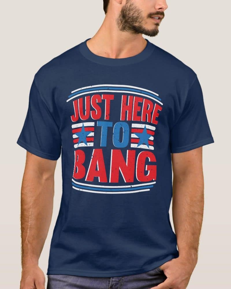 Man wearing a navy blue t-shirt with red, white, and blue text that says Just Here To Bang.