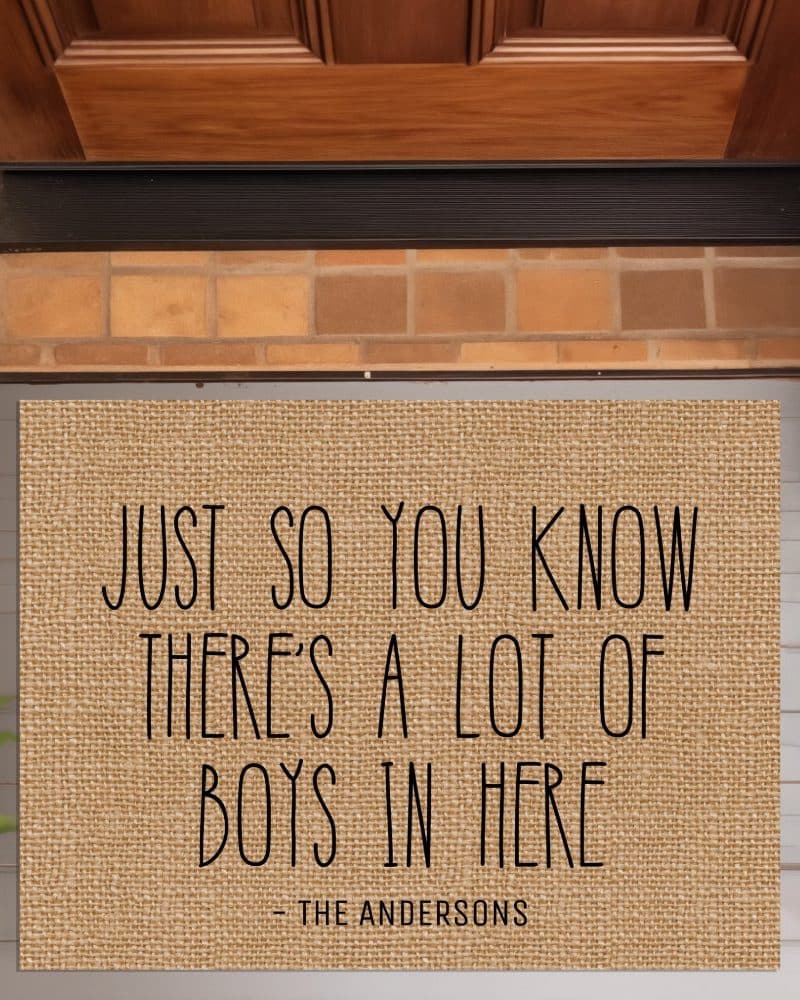 A tan burlap doormat with the text: Just so you know there's a lot of boys in here, signed The Andersons.