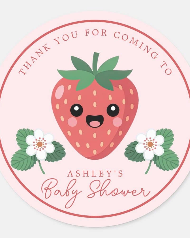 Pink circle thank you sticker for Ashley's baby shower, featuring a cartoon strawberry with a happy face and small white flowers.