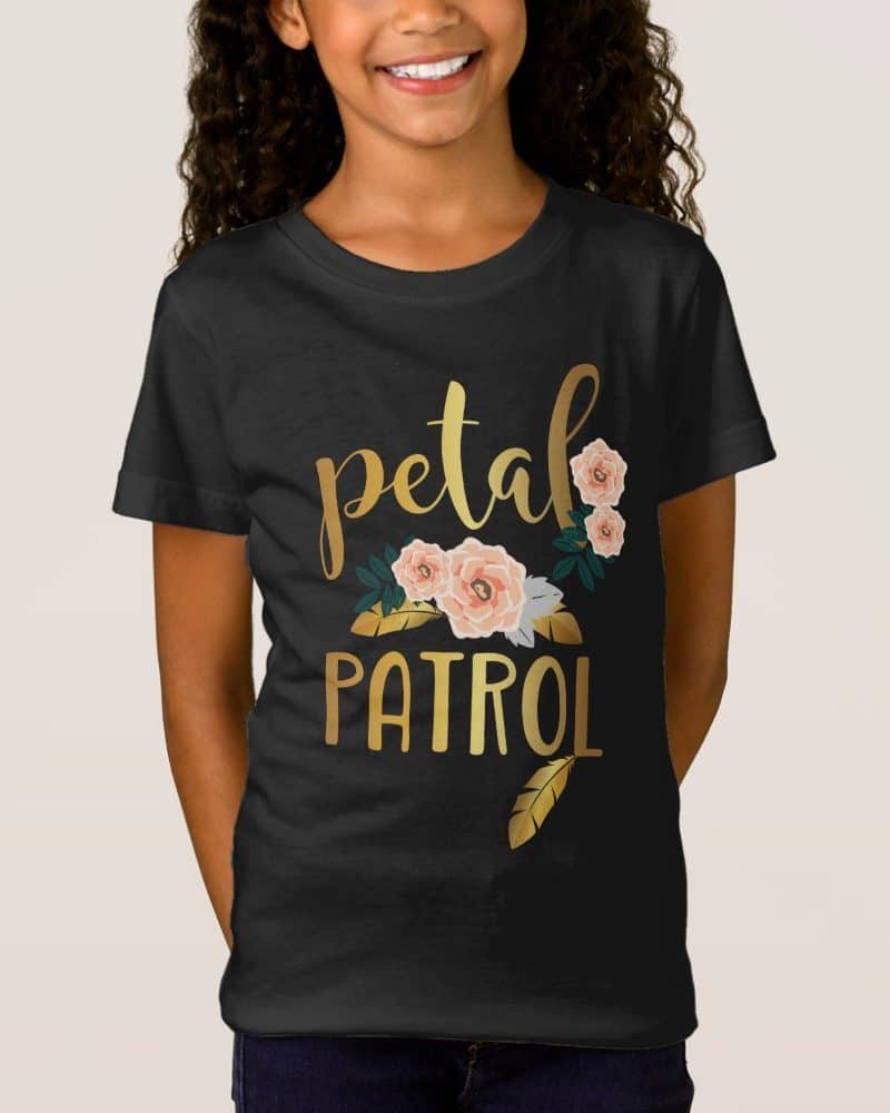 Girl wearing a black t-shirt with gold lettering that says Petal Patrol and peach flowers.