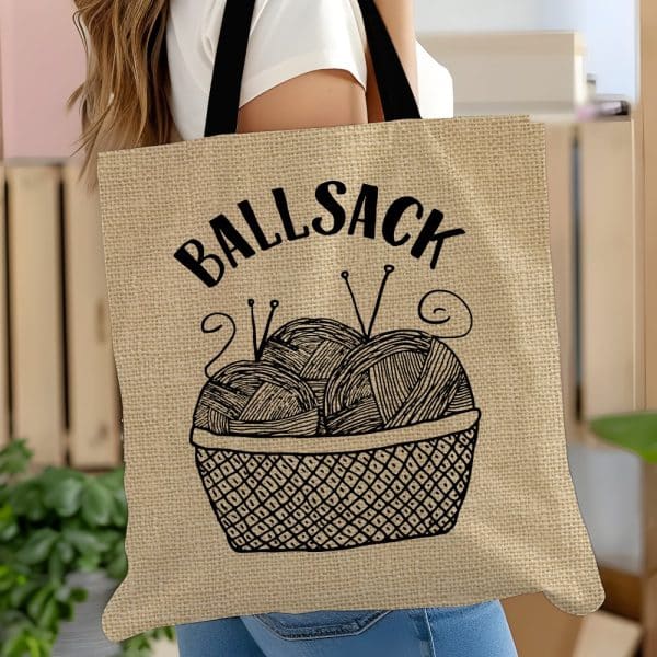 Beige Tote Bag With Black Text Reading Ballsack And A Drawing Of A Basket Of Yarn.