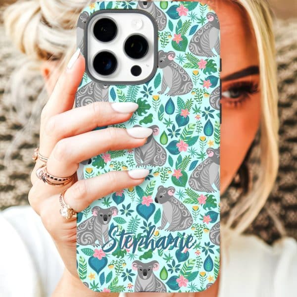 A Woman'S Hand Holds A Teal Iphone Case Featuring A Repeating Pattern Of Koalas And Tropical Flowers. The Name Stephanie Is Printed On The Case.
