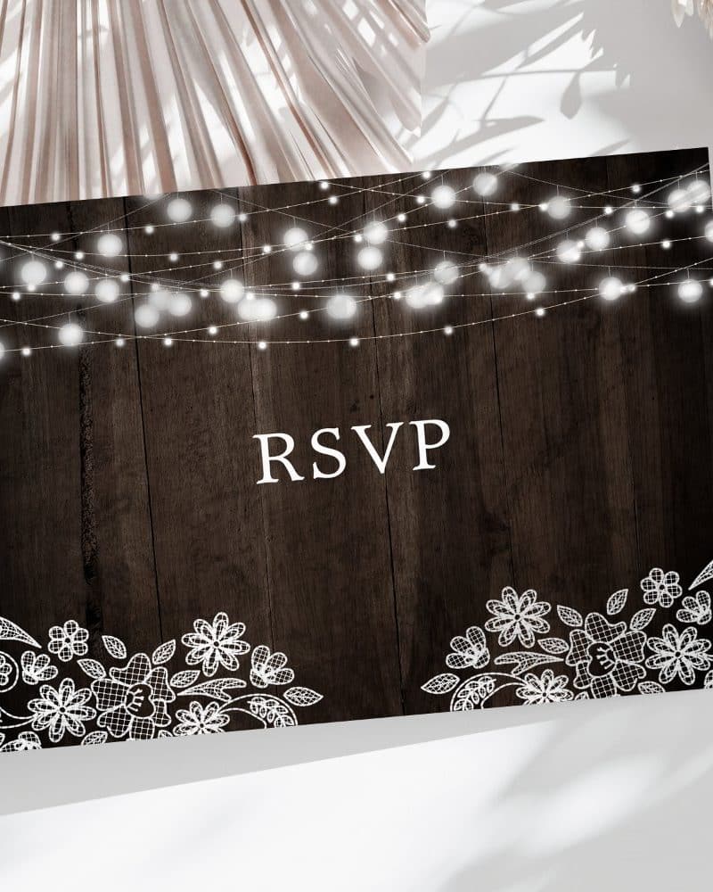 RSVP card with dark wood background, string lights at the top, and white lace at the bottom.