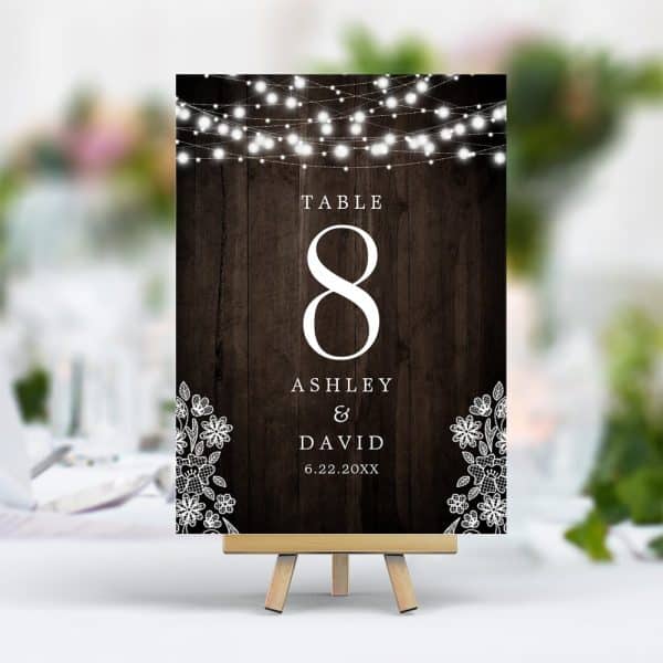 Wedding Table Number Eight For Ashley And David, Displayed On A Dark Wood Sign With String Lights And Lace Accents.