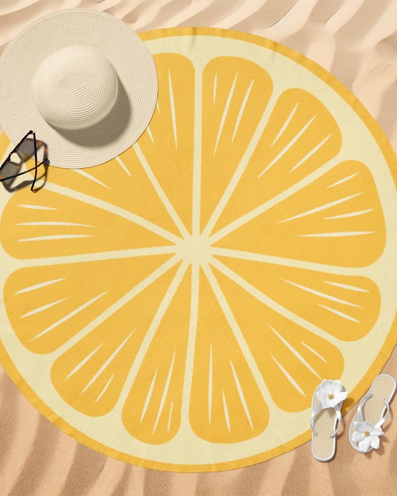 Round lemon slice beach towel on sand.