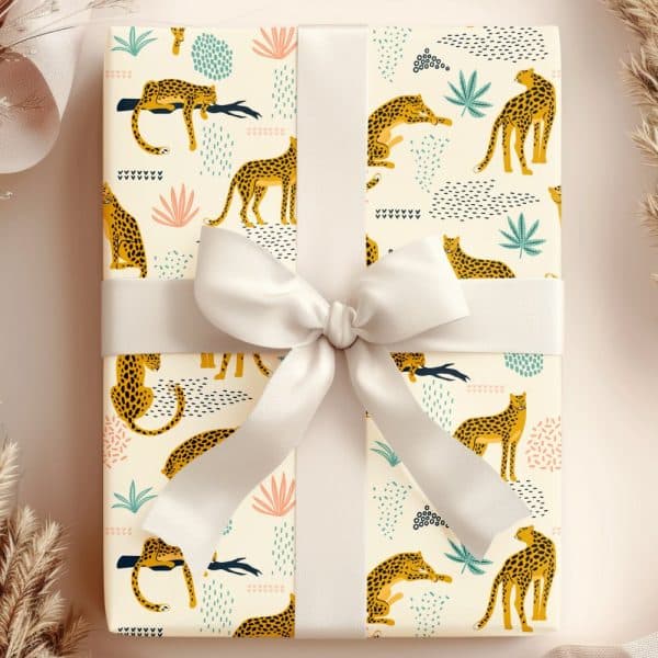 Gift Wrapped In Off-White Paper With A Pattern Of Yellow Leopards And Abstract Shapes. A Large Off-White Bow Is Tied On Top.