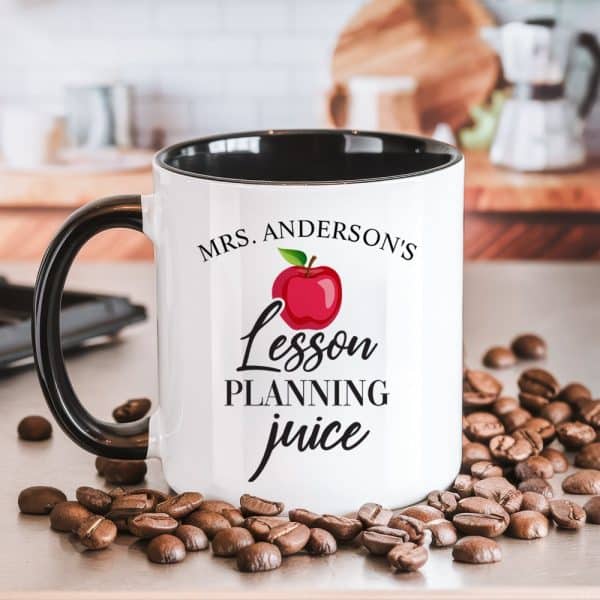 White Coffee Mug With Black Handle And Rim, Displaying The Text Mrs. Anderson'S Lesson Planning Juice And A Red Apple Graphic.
