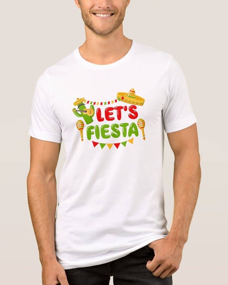 A man is modeling a white t-shirt with a festive design. The design includes the text Lets Fiesta, along with a cactus playing a guitar, maracas, and a sombrero.