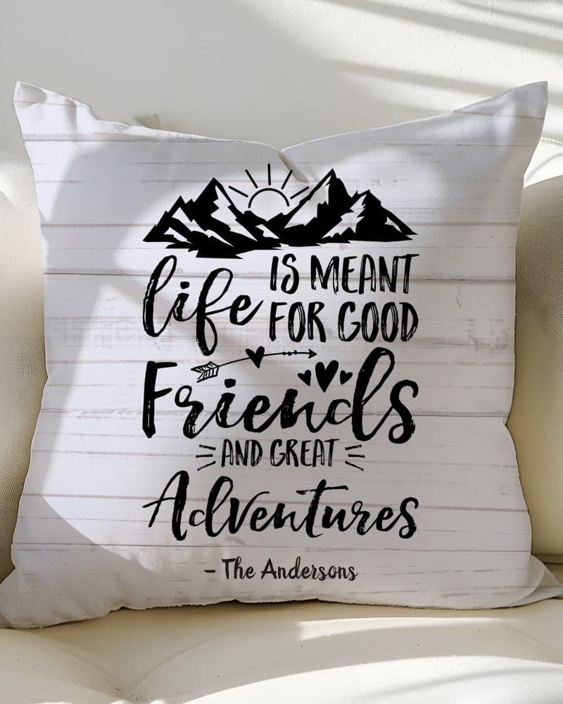 White throw pillow with black text and mountain graphic; the text reads Life is meant for good friends and great adventures.
