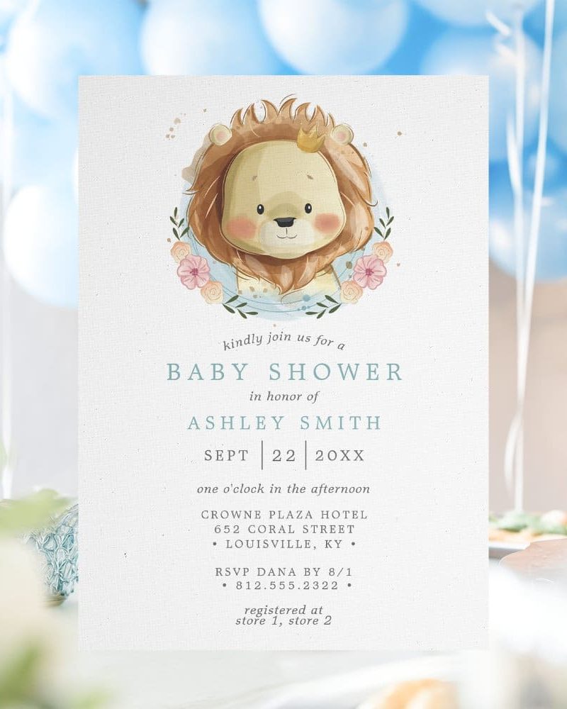 Baby shower invitation featuring a cute lion wearing a crown and surrounded by flowers.