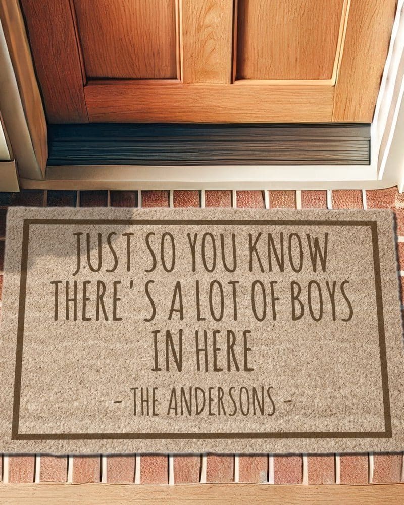 Beige doormat with brown text reading, Just so you know there's a lot of boys in here, signed The Andersons.