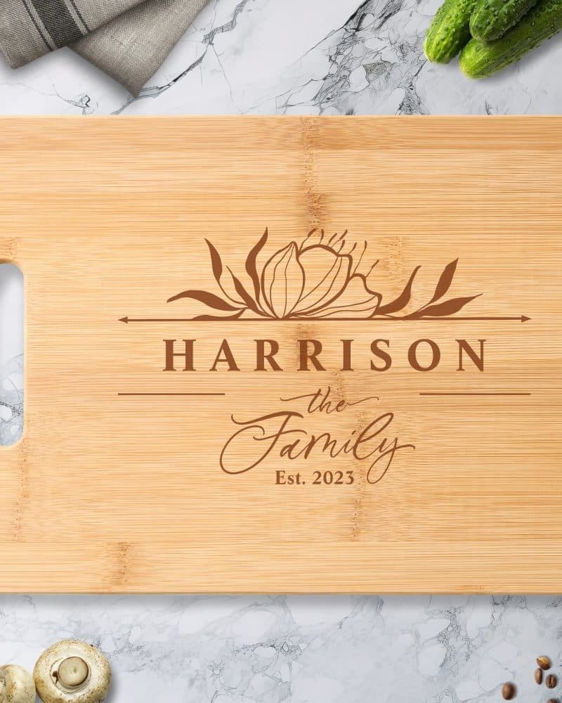 Light brown bamboo cutting board with a floral design and the engraved text Harrison the Family Est. 2023.
