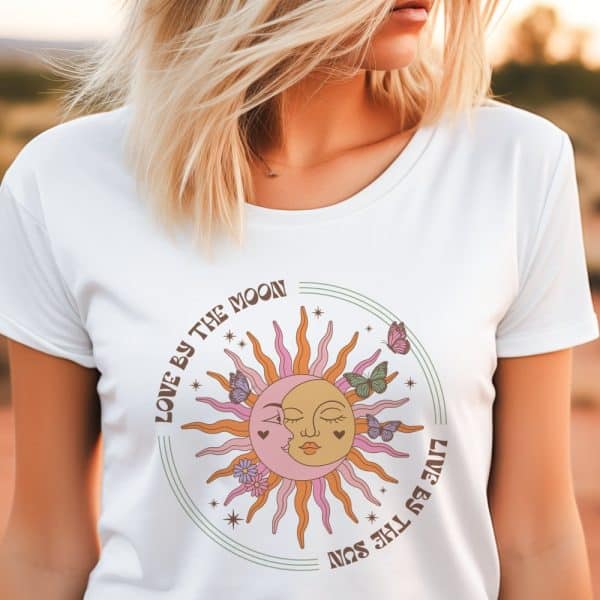 Woman Wearing A White T-Shirt Featuring A Sun And Moon Design With Butterflies And The Text Love By The Moon, Live By The Sun.