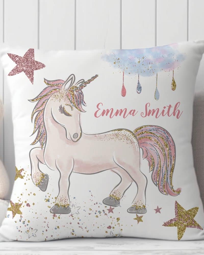White pillow with a sparkly pink and gold unicorn, stars, and the name Emma Smith.