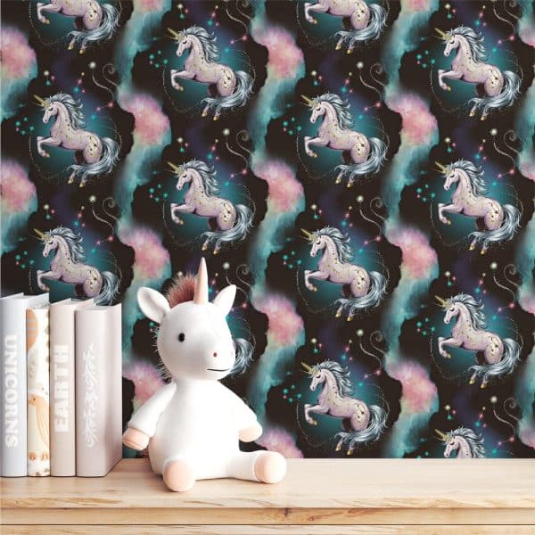 A White Unicorn Stuffed Animal Sits In Front Of Wallpaper Featuring A Repeating Pattern Of Pink And Teal Unicorns Against A Dark Background.