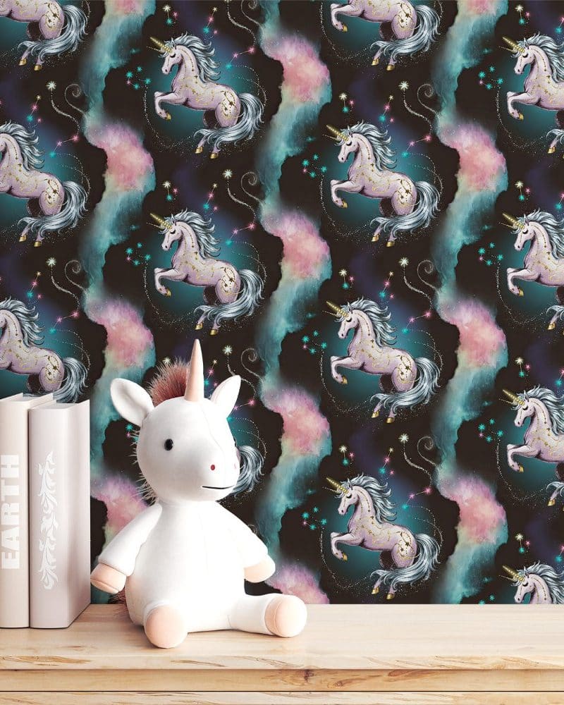 A white unicorn stuffed animal sits in front of wallpaper featuring a repeating pattern of pink and teal unicorns against a dark background.
