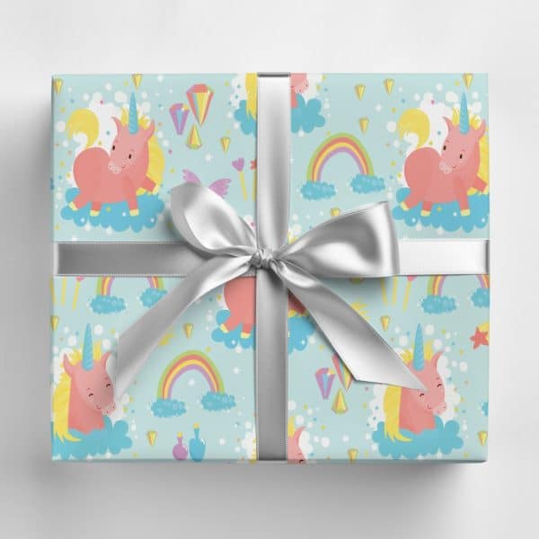 Gift Box With A Light Blue Wrapping Paper Featuring A Pattern Of Pink Unicorns, Rainbows, And Stars. A Silver Ribbon Is Tied In A Bow On Top.