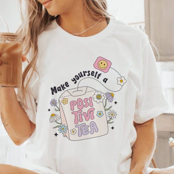 Woman Wearing A White T-Shirt With A Graphic Design Of A Tea Bag That Says Positivitea.